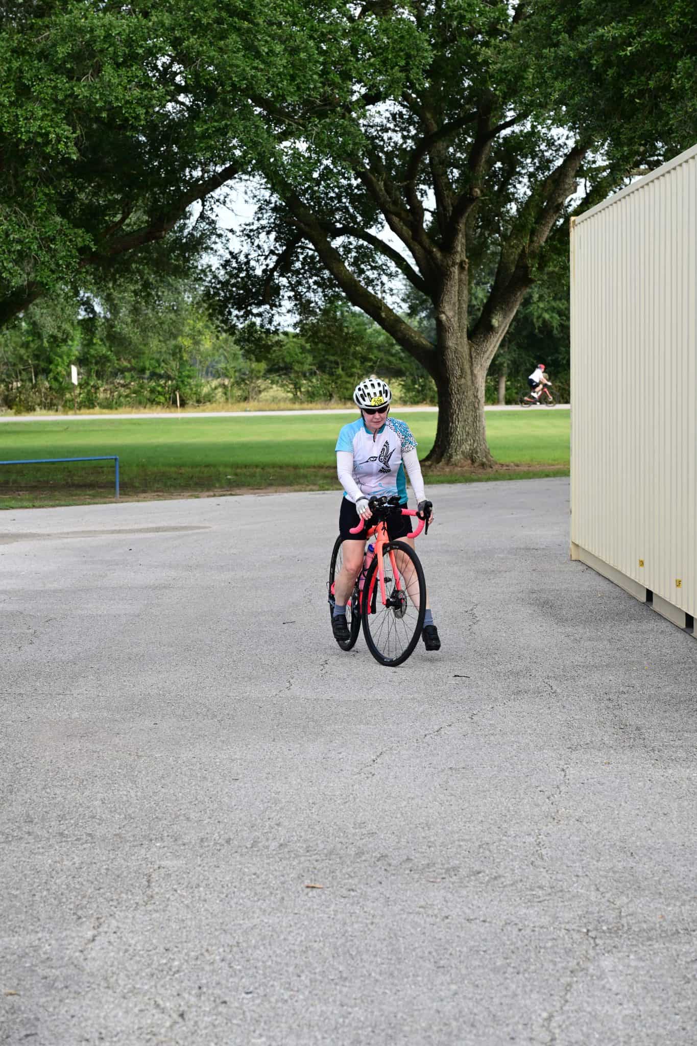 Cyclist riding bike near large tree during Katy Flatland Century event.